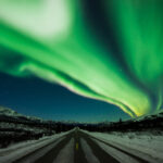 Neon green northern lights dancing over the road in Denali National Park, Alaska